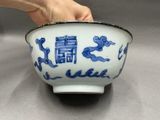 a person holding a bowl with blue and white designs on it