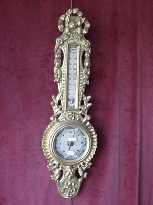 une horloge dorée accrochée au mur, avec un rideau rouge en arrière-plan