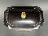 a small black tray with a gold ring on it