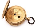 a gold pocket watch on a white surface with a key