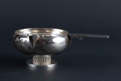 a silver bowl with a spoon in it on a black surface