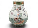 un vase blanc orné d'un motif vert et rouge