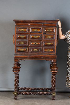 une femme vêtue d'une robe à imprimé léopard, debout à côté d'une grande armoire en bois