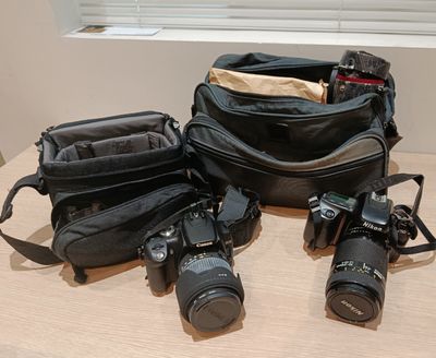 three cameras and a camera bag on a table