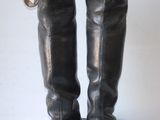 pair of black leather boots sitting on top of a white table