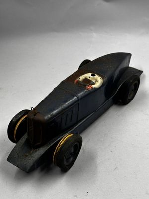 une petite voiture noire avec un chien à l'avant