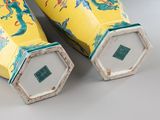 pair of yellow vases with dragon designs on them sitting on a table