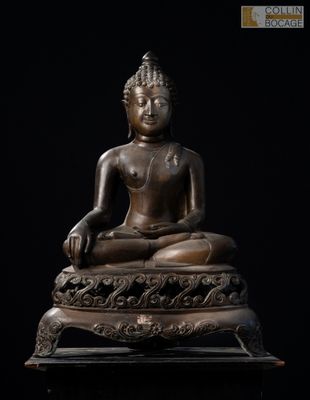 une statue en bronze représentant un Bouddha assis sur un fond noir