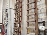 plusieurs échelles en bois appuyées contre un mur dans un entrepôt
