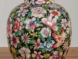 un vase coloré posé sur une table, avec des fleurs à l'intérieur