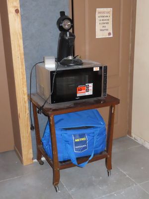 un micro-ondes posé sur une petite table, sur laquelle se trouve un sac bleu