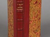 an old book with a red cover sitting on top of a table