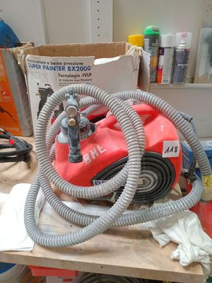 une photo d'un aspirateur rouge et gris posé sur un établi