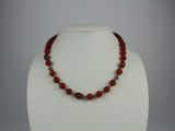a close up of a necklace on a mannequin with a red bead