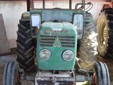 a green tractor parked in front of a building