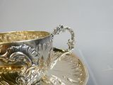 a silver cup and saucer sitting on a silver plate