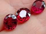 deux pierres précieuses de couleur rubis posées sur le doigt d'une personne