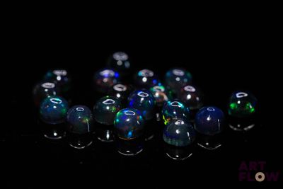 a lot of blue and green glass beads on a black surface