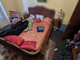 une photo d'une chambre avec un lit et des vêtements par terre