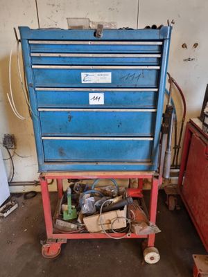 une boîte à outils bleue posée sur un chariot rouge dans un garage