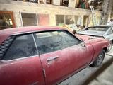 many old cars parked in a garage with a man standing next to them