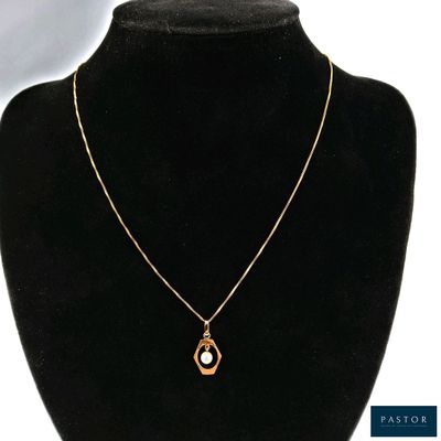 un collier en or avec un pendentif en perle autour du cou d'un mannequin