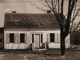 a black and white photo of a house with a tree in front of it
