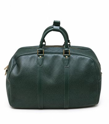 un sac de voyage en cuir vert posé sur une surface blanche