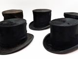 several black top hats are lined up in a row on a white surface