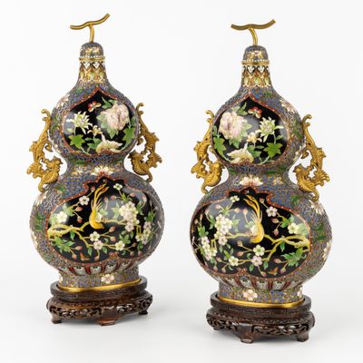 pair of vases with floral decoration on stands on a white background