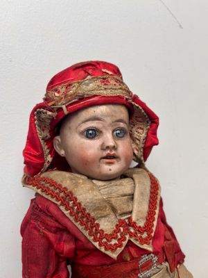 a small doll that is wearing a red dress and a red hat