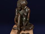 bronze statue of a boy sitting on a pedestal with a book in his lap