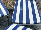 three blue and white striped lounge chairs and one is empty