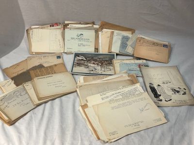 a lot of old letters and envelopes sitting on a bed