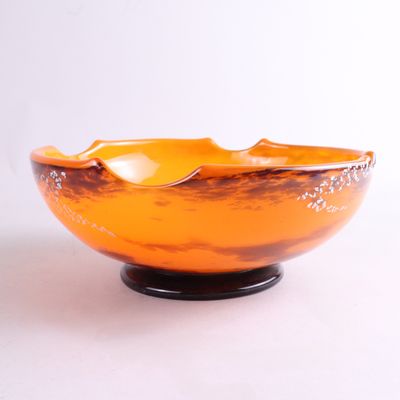 un bol orange posé sur un socle noir, lui-même posé sur une surface blanche