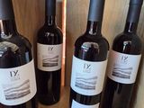 six bottles of wine are lined up on a wooden shelf