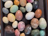 many different colored eggs in a black tray on a table