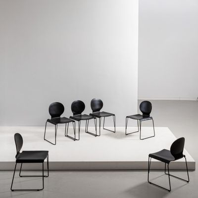 three black chairs sit on a white platform in a white room