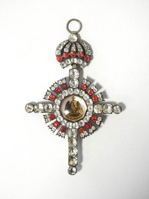 une image représentant une croix en argent ornée de pierres rouges et blanches
