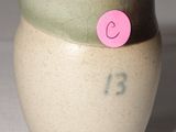 un petit vase sur lequel est collé un autocollant rose