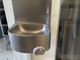 un évier en acier inoxydable dans le coin d'une salle de bains