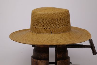 un chapeau de paille posé sur un support en bois