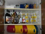de nombreuses bouteilles et verres sur les étagères du placard