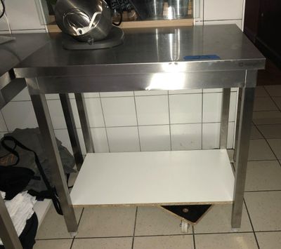 une table en acier inoxydable avec une étagère en dessous, dans une cuisine