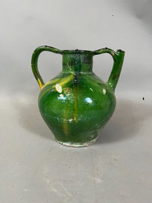 un vase vert posé sur une surface blanche