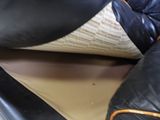 a close up of a black leather couch with a white pillow