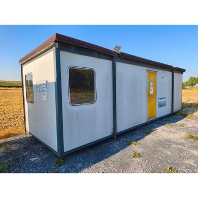 un petit bâtiment avec une porte jaune au milieu d'un champ