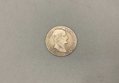 un gros plan d'une pièce de monnaie posée sur une table, sur fond gris