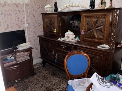 un salon avec un vaisselier en bois et un fauteuil bleu