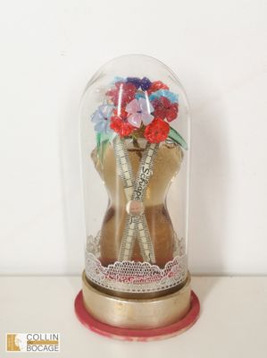 une cloche de verre dans laquelle se trouve un ours en peluche tenant un bouquet de fleurs